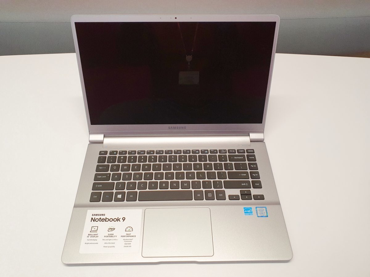 Silver laptop with a black keyboard and touchpad, opened on a white desk