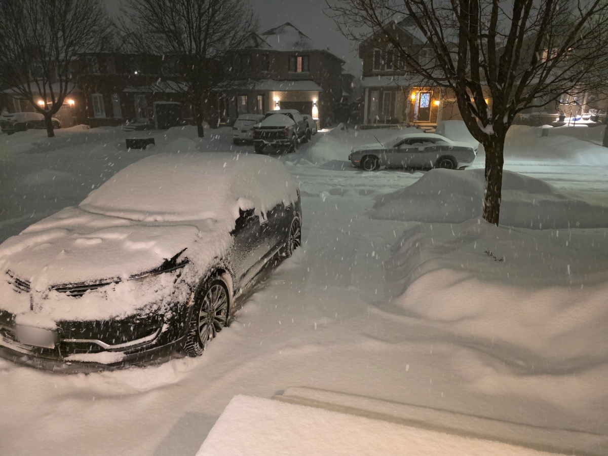 Snow-covered car parked on a residential street during a Toronto snowstorm