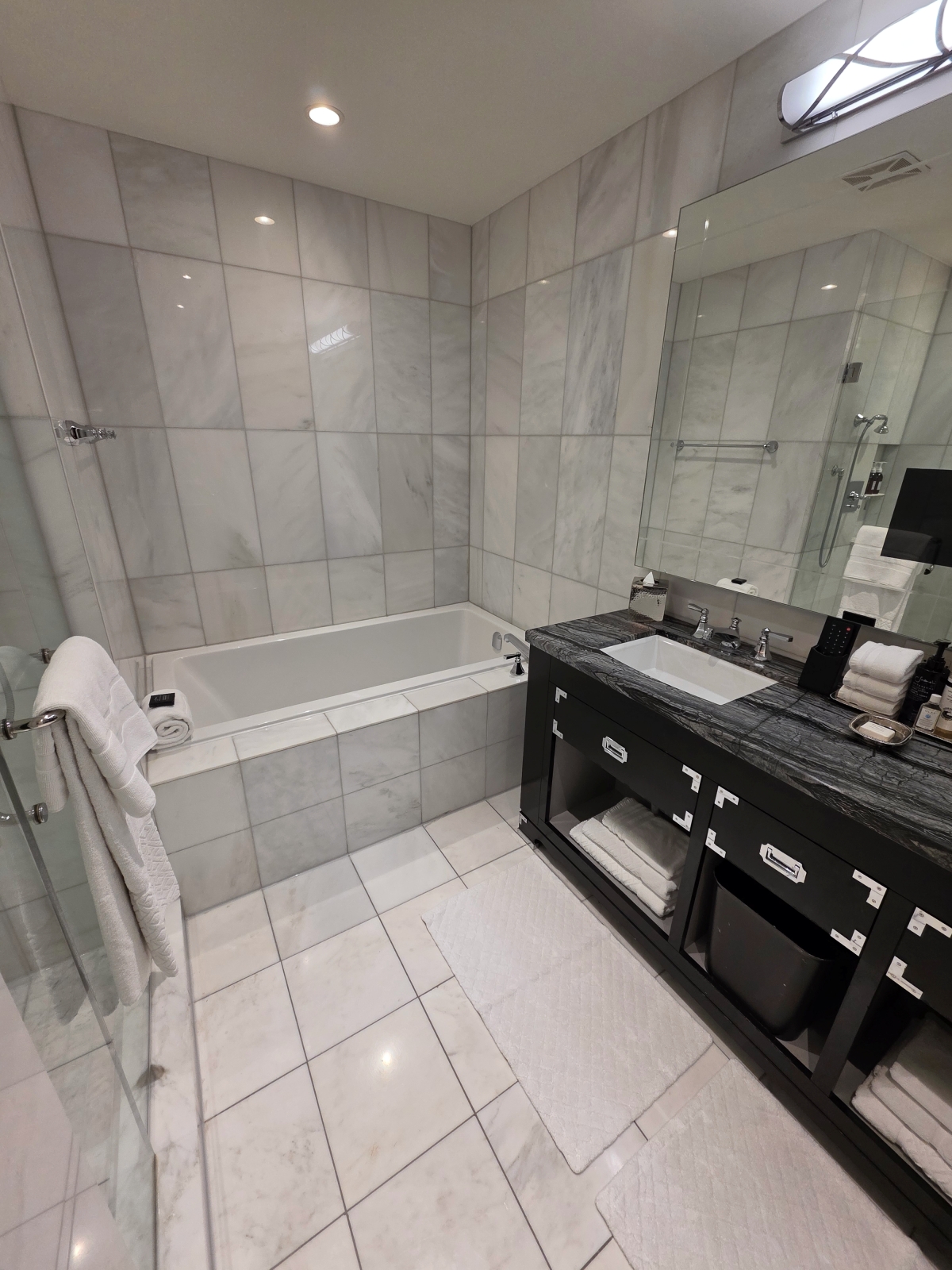 Full view of the spacious marble guest bathroom with tub, shower, and double vanity