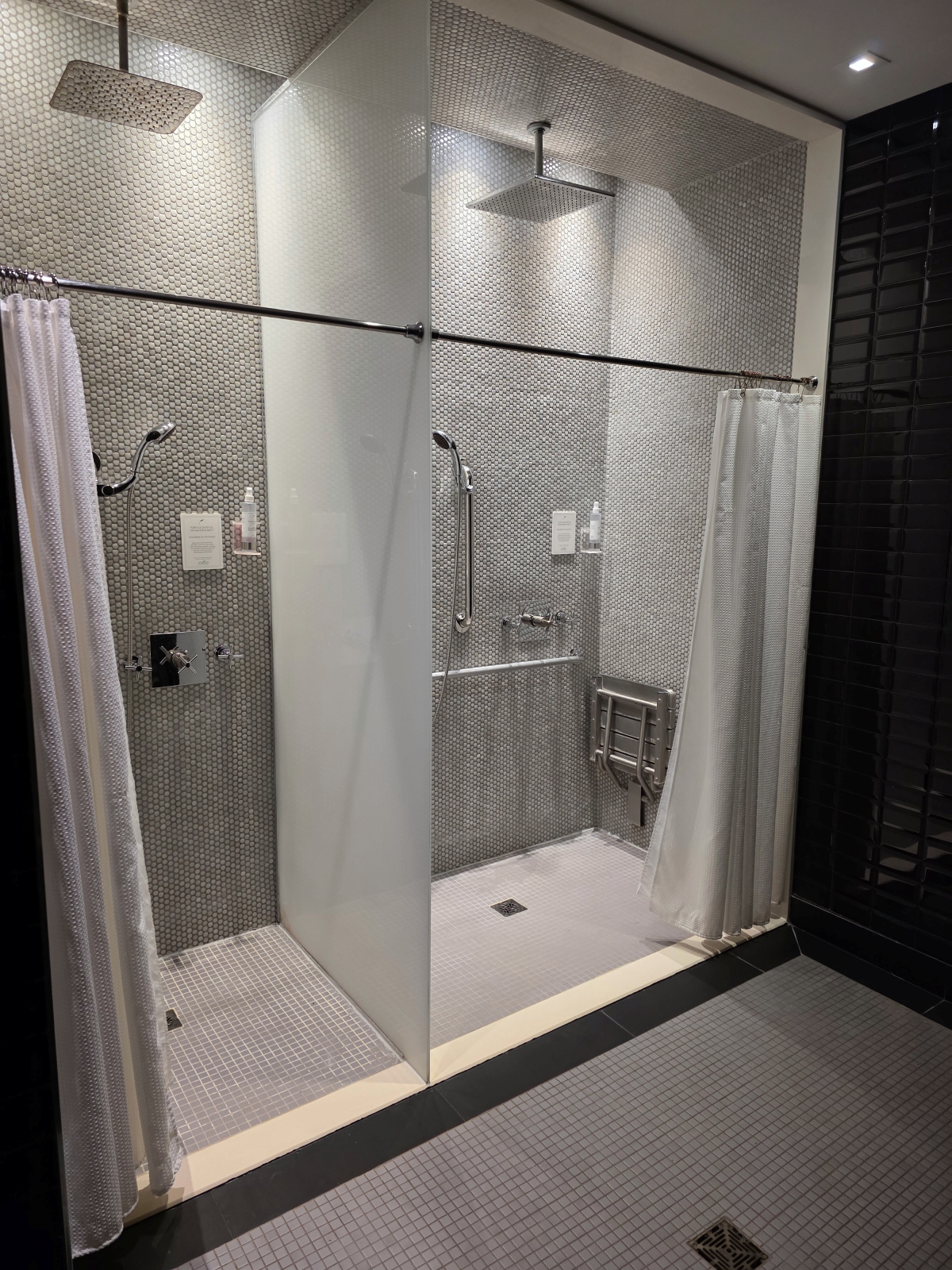 Modern walk-in shower with glass doors and grey tiling in the spa locker room