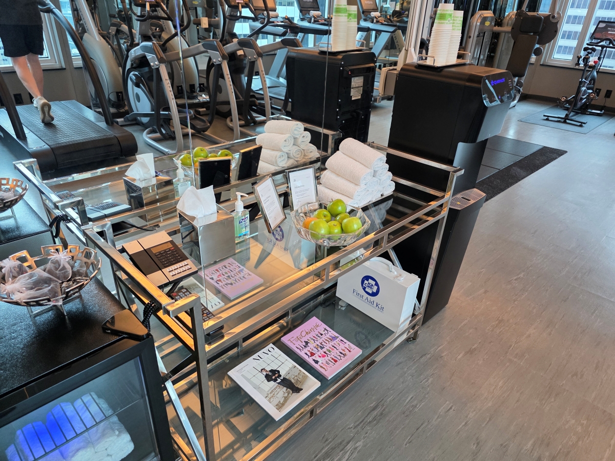 Complimentary bottled water, fresh fruit, and towels on a cart in the hotel gym