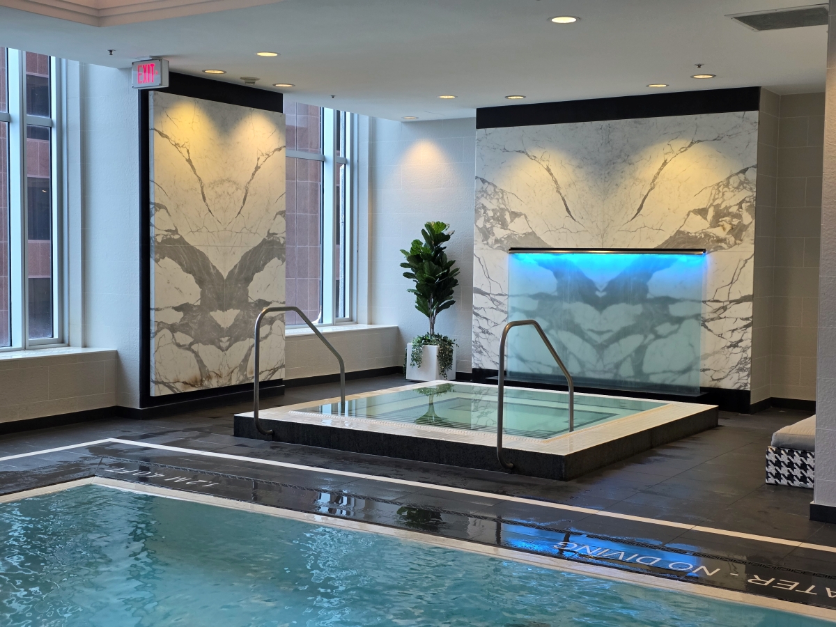 Elevated square indoor jacuzzi whirlpool next to the main swimming pool