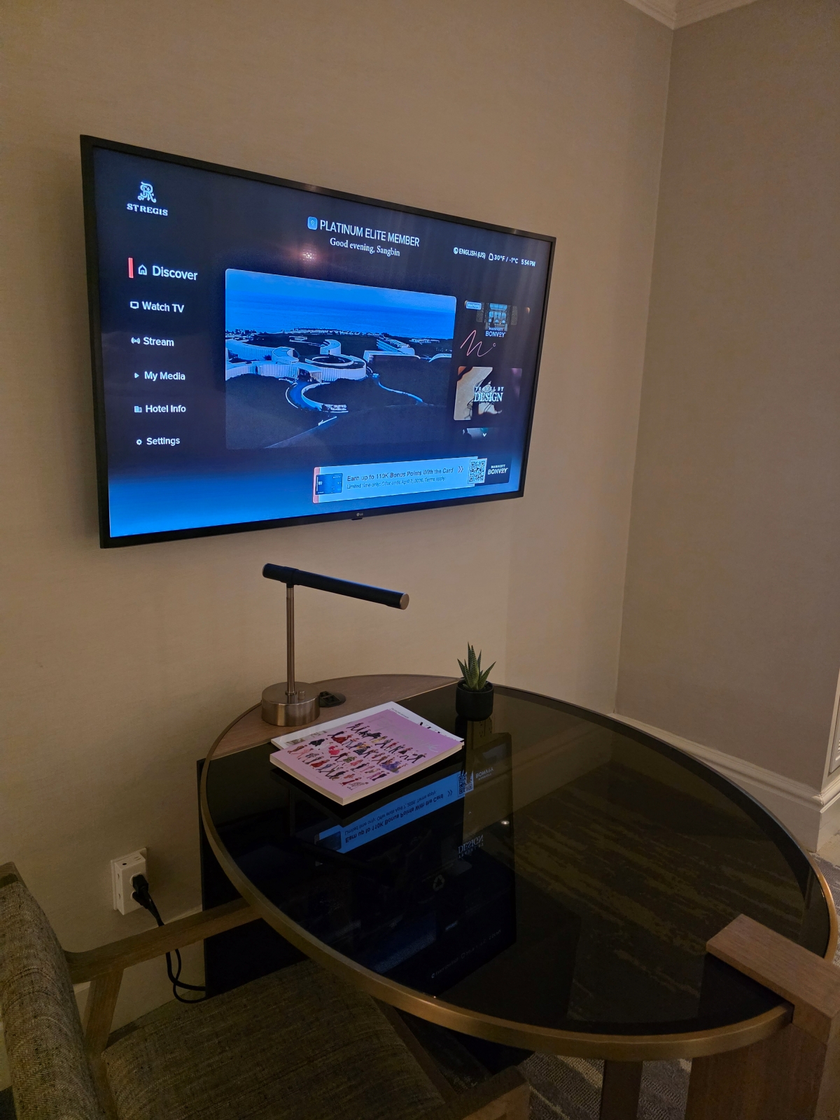 The hotel suite's living room area featuring a flat-screen TV and round table