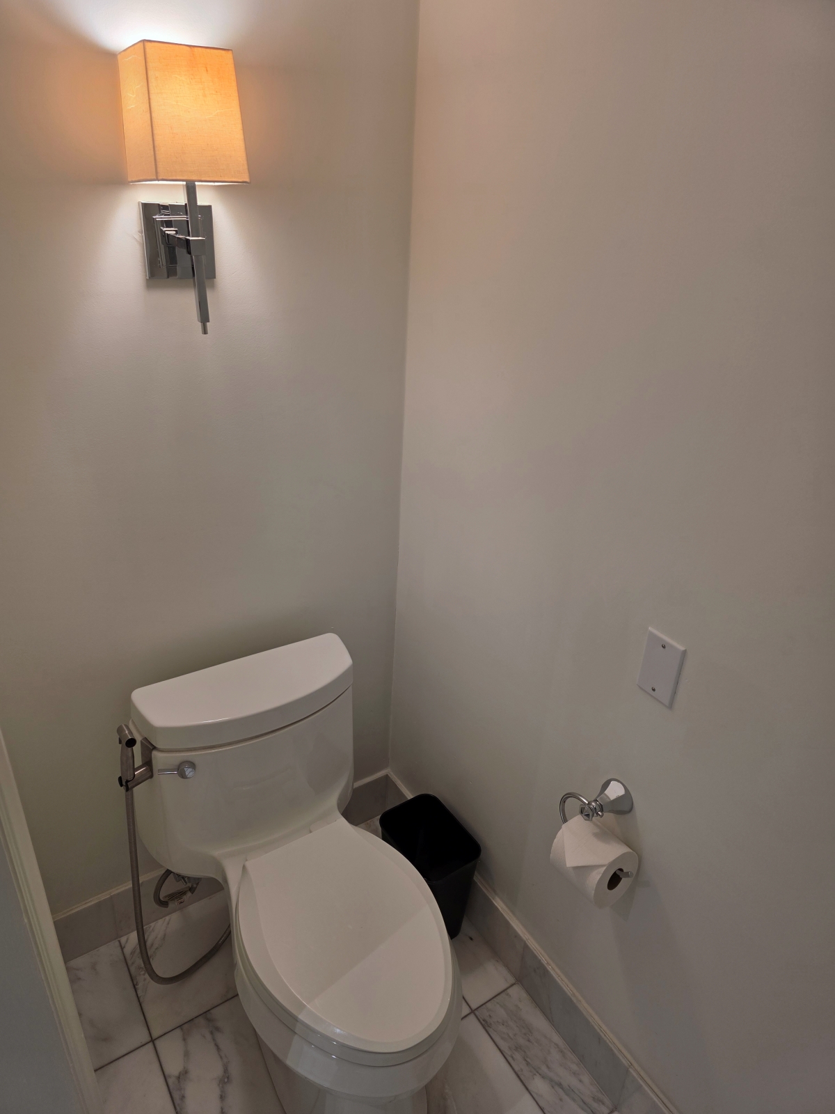 A clean, brightly lit private toilet area in the hotel guest bathroom