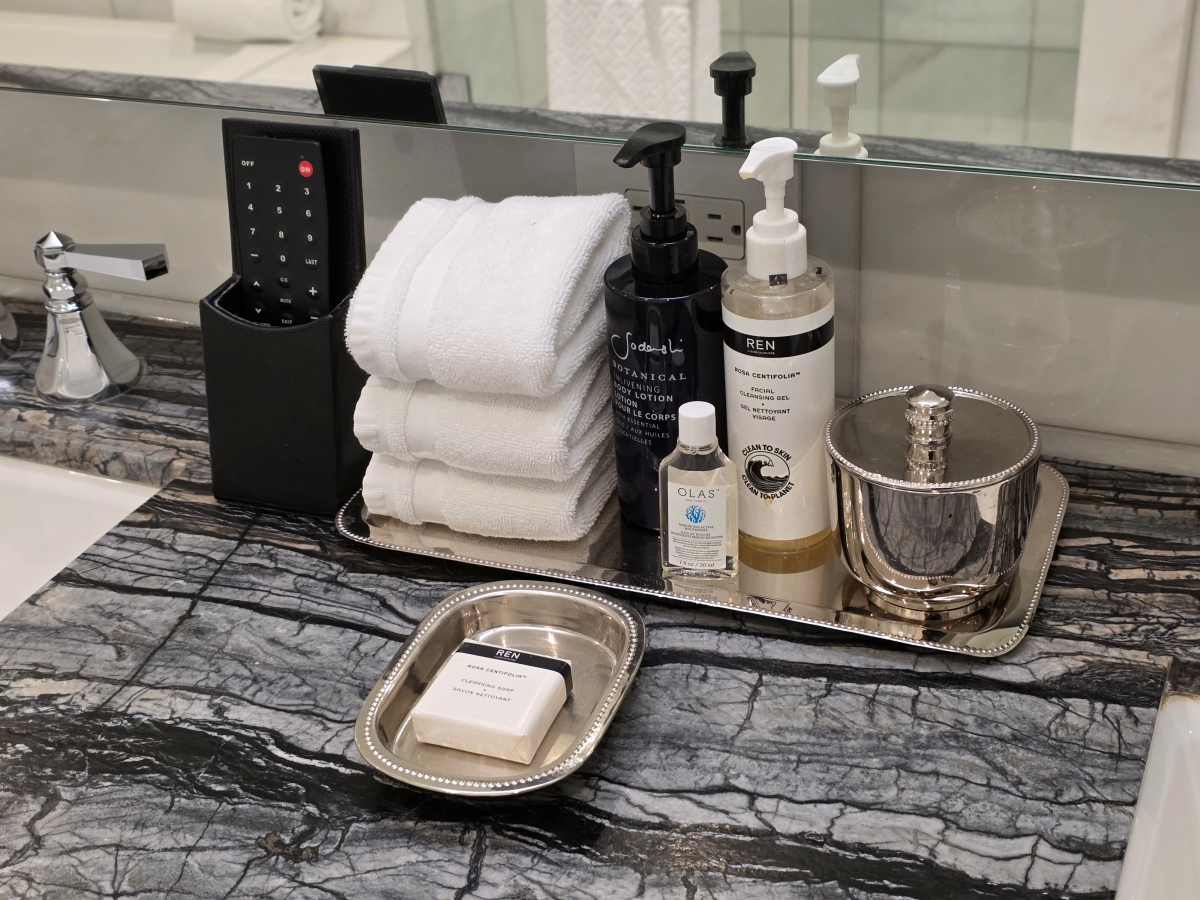 Marble bathroom sink area with rolled towels, soap, and amenities