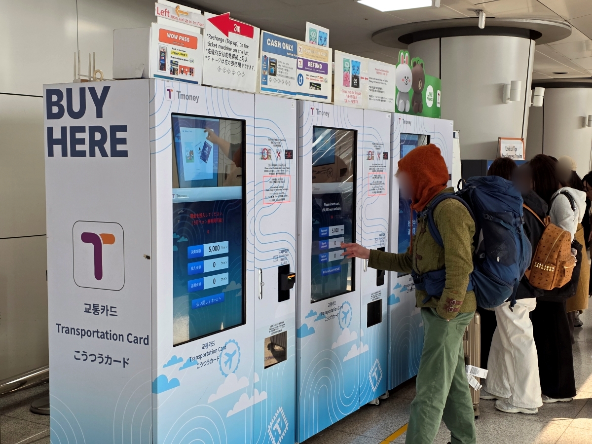 Travelers using automated ticket vending machines to buy AREX tickets or reload T-money cards