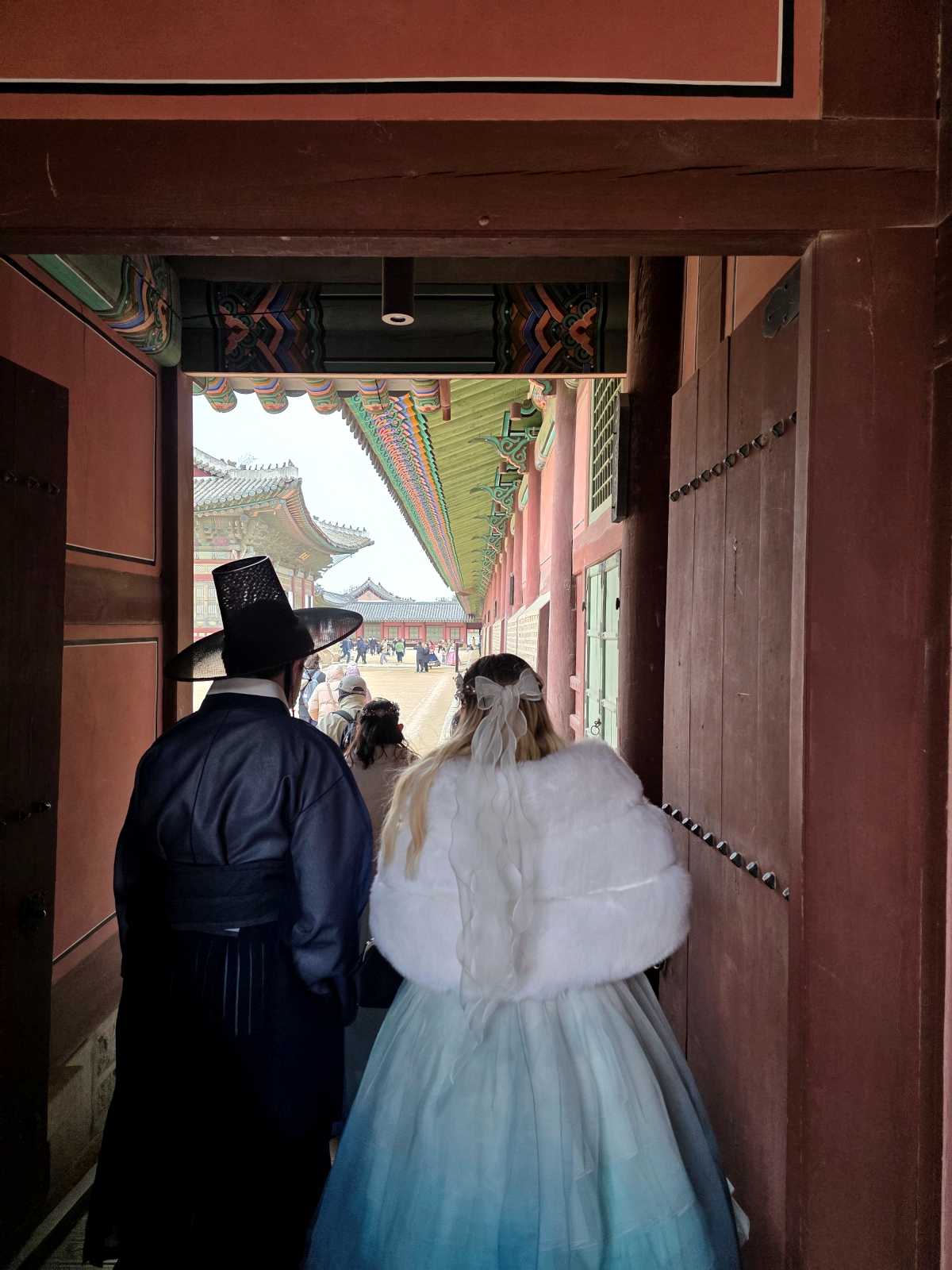 A couple in Hanbok walking through a traditional palace gate