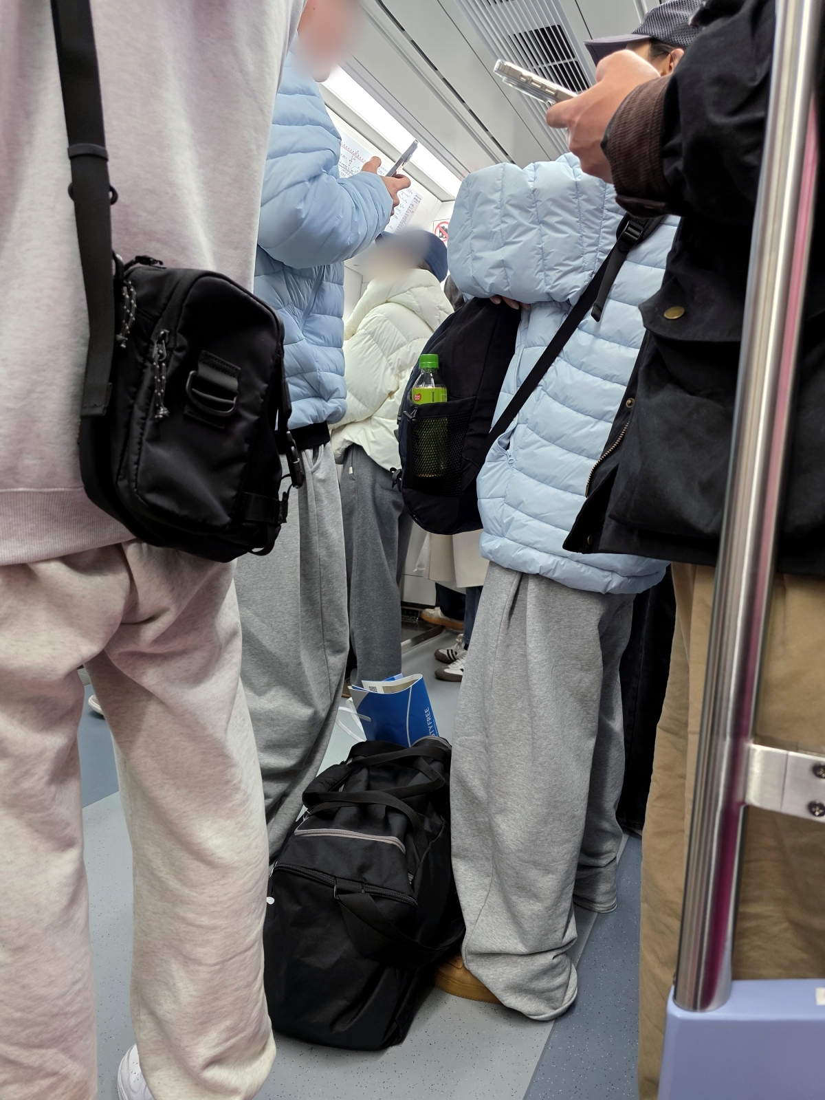 A traveler standing on the AREX train while holding onto their large suitcase