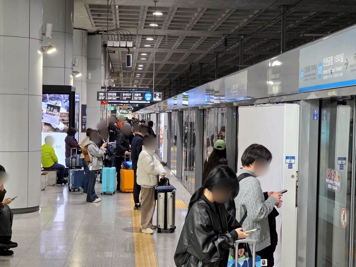 Travelers with luggage boarding the AREX train from the platform
