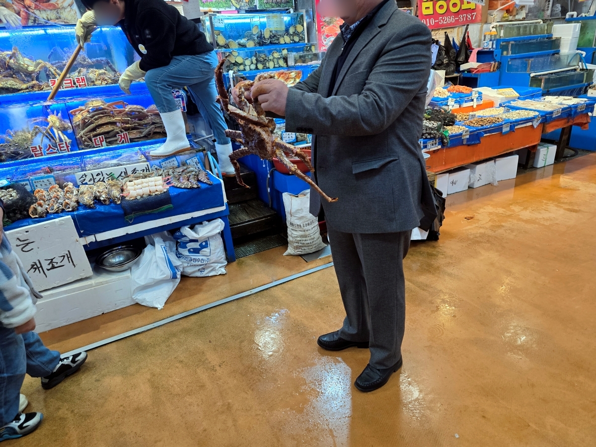 Buyer holding king crab at Seoul fish market Noryangjin taking a photo